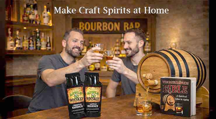 Two men sitting at a home bar labeled “Bourbon Bar” clink glasses of whiskey while smiling. On the counter are two bottles of whiskey essence flavoring, a small wooden aging barrel, and a book titled The Bootlegger’s Bible: A Spiritual Guide to Aging, with the text “Make Craft Spirits at Home” displayed at the top of the image.